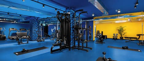Un gimnasio con diversos equipos de ejercicio, incluyendo cintas de correr, máquinas de pesas y mancuernas.
