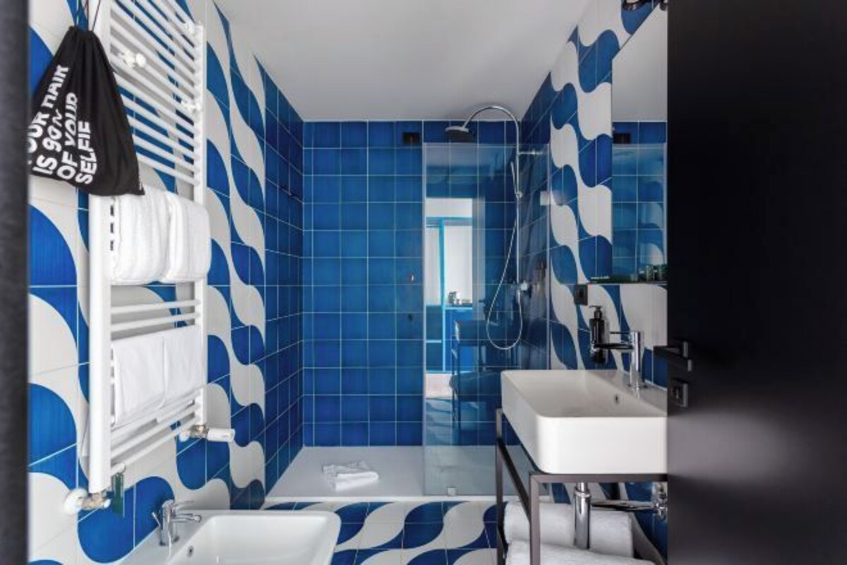 Une salle de bain moderne avec des carreaux bleus à motifs, un lavabo blanc et une douche.