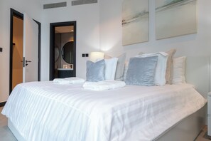 A neatly made bed with white linens and pillows, a bedside lamp, and a wall-mounted artwork. - Luxury 1-Bedroom Apartment, Burj Khalifa Views & Infinity Pool, Dubai Mall (Dubai)