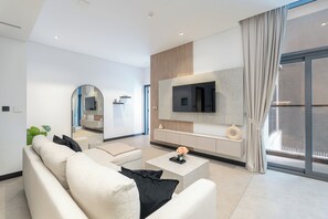 A modern living room with a sofa, coffee table, and a flat-screen TV mounted on the wall. - Luxury 1-Bedroom Apartment, Burj Khalifa Views & Infinity Pool, Dubai Mall (Dubai)