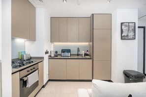 A compact kitchen with modern appliances, a built-in oven, and a sink. - Luxury 1-Bedroom Apartment, Burj Khalifa Views & Infinity Pool, Dubai Mall (Dubai)