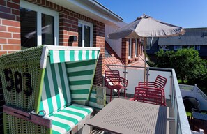 Un patio con una sedia a righe, un tavolo e una sedia rossa.