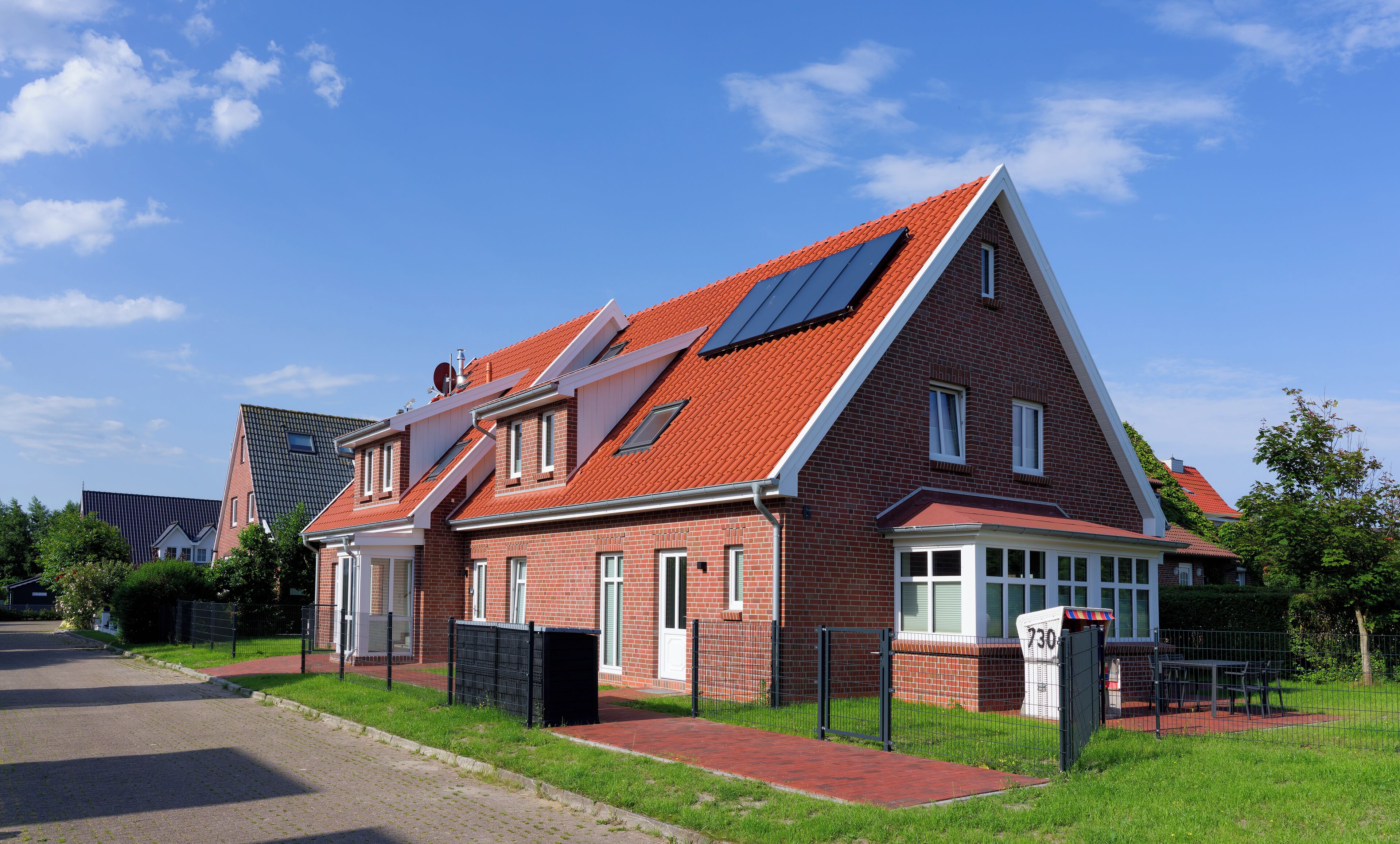 Ein zweistöckiges Haus mit rotem Ziegeldach, einem sichtbaren Dachboden und einer Ziegelaußenwand.