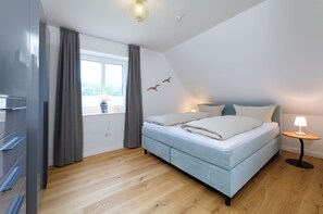 Una camera da letto moderna con un letto grande, un comodino con una lampada, un armadio e una finestra con tende.