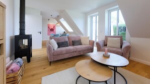 En hyggelig stue med en moderne pejs, et lyserødt sofasæt og et rundt bord.