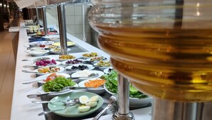 A buffet line with various food items and a wine dispenser. - Hôtel EL AZIZ INN (Algiers)