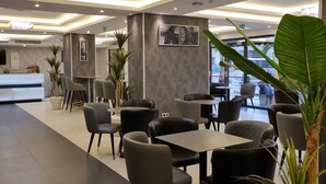 A modern restaurant interior with a reception desk, seating area, and decorative elements. - Hôtel EL AZIZ INN (Algiers)