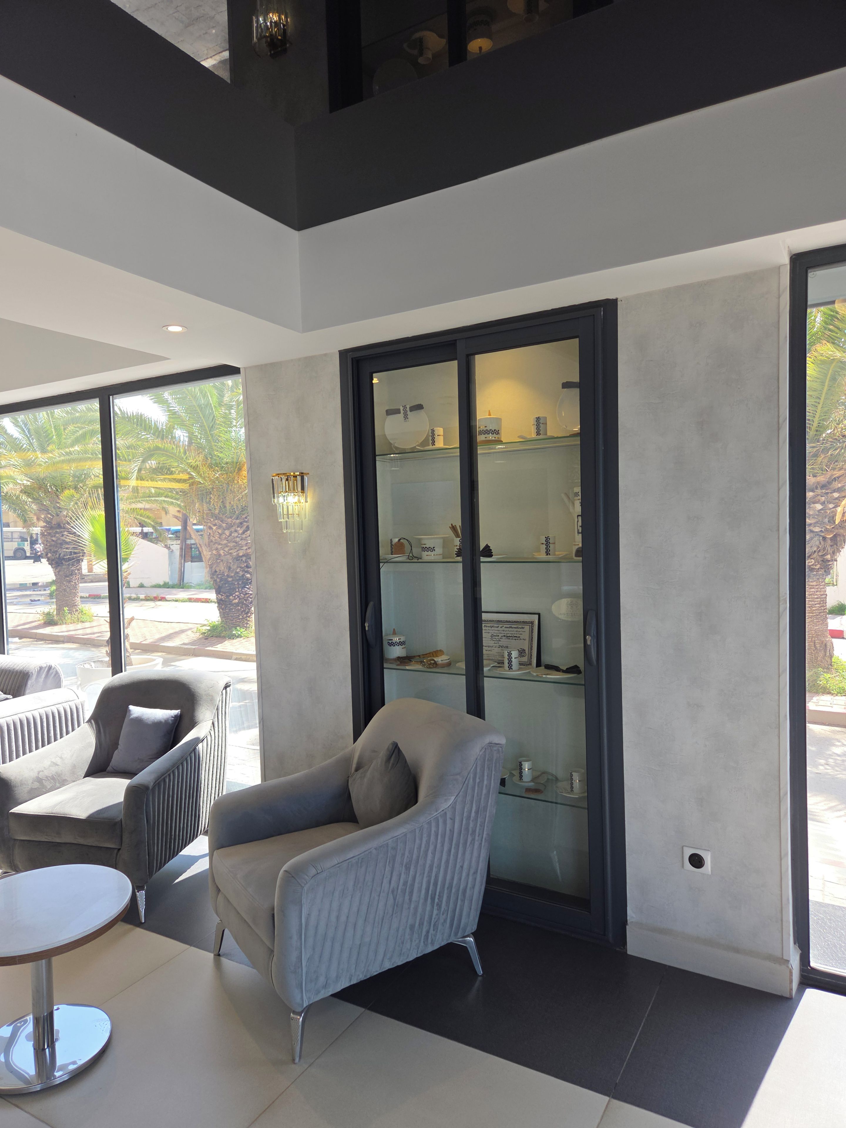 Un intérieur moderne comprenant un coin salon, une vitrine et de grandes fenêtres.