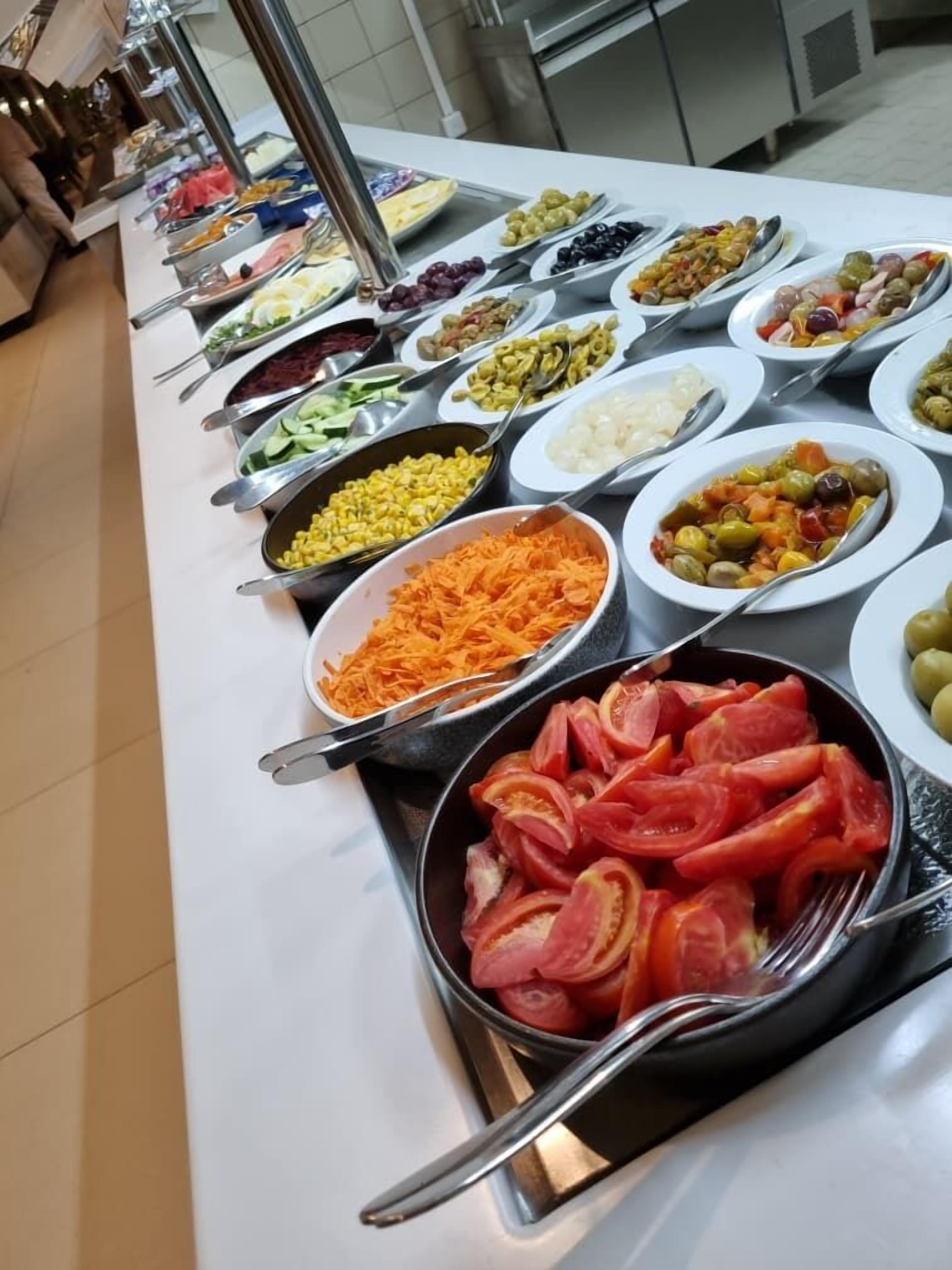Een buffet met diverse gerechten, waaronder salades, groenten en vlees.