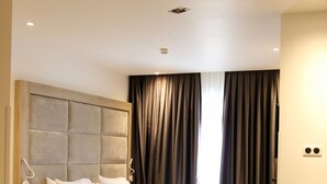 A modern hotel room with a large bed, a wooden nightstand, a desk, and a large window with curtains. - Hôtel EL AZIZ INN (Algiers)