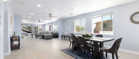 A spacious living area with a dining table, chairs, and a sofa.