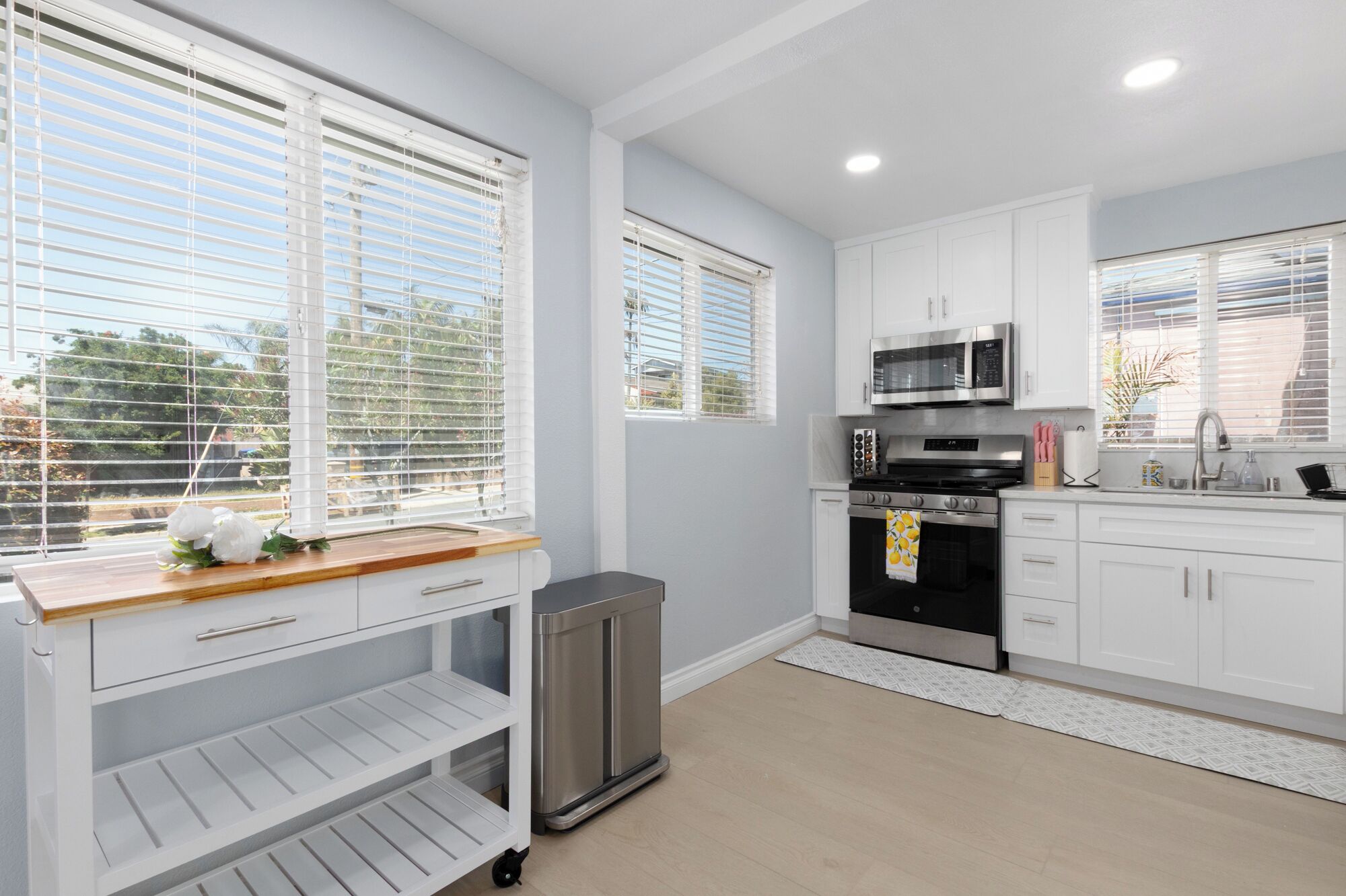 A modern kitchen with white cabinets, stainless steel appliances, and a wooden countertop.