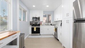 Una cocina moderna con armarios blancos, electrodomésticos de acero inoxidable y encimera de madera.