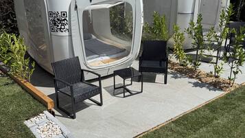 Two modern, white, semi-transparent tents with QR codes, black metal chairs, and a small table.
