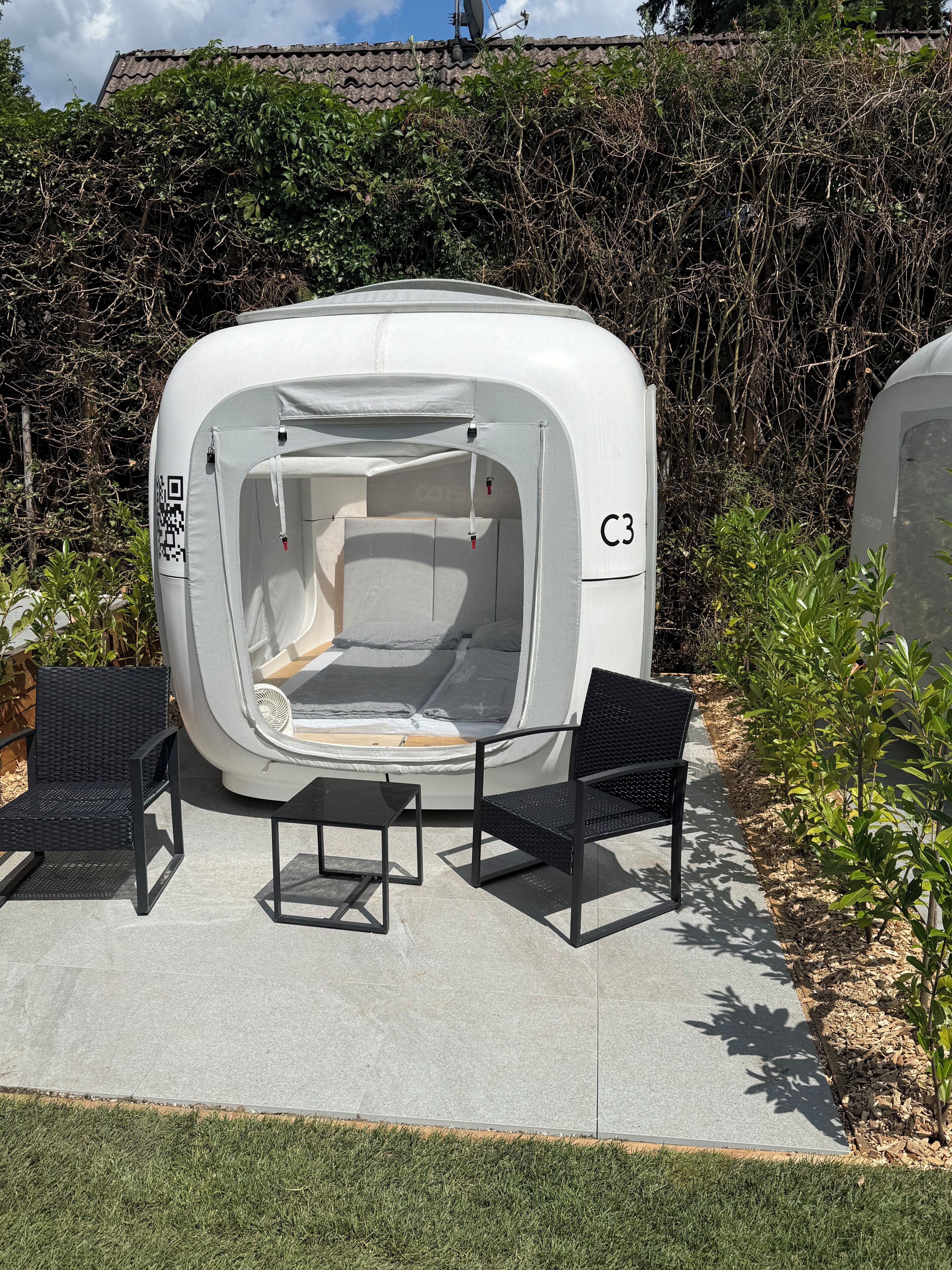 Une tente avec un code QR, portant l’inscription « C3 », et deux chaises noires devant.