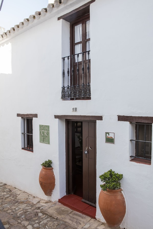 Un edificio blanco con un balcón, una puerta y dos macetas.
