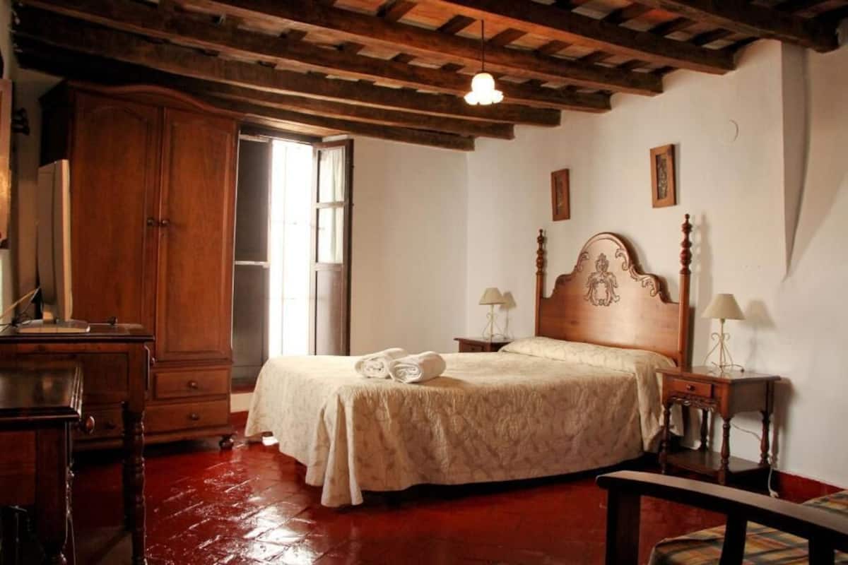 A bedroom with a wooden bed, a wardrobe, a desk, and a chair.