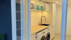 Ett kompakt kök med en diskho, en arbetsbänk och en tvättmaskin, inramat av en vit ram.