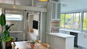 Ett modernt kök med vita skåp, en köksö och en matplats med ett träbord och stolar.