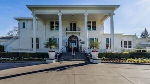 A large, two-story building with a symmetrical facade, central entrance, and a covered porch with columns. - Napa Valley Getaway in Silverado (Napa)