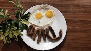 A plate with a fried egg, sausages, and a plant. - The Local Tribe Homestay Cafe & Hostel (Darjeeling)