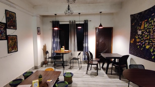 A dining area with a wooden table, chairs, and a hanging light fixture. - The Local Tribe Homestay Cafe & Hostel (Darjeeling)
