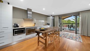 Una cocina moderna con armarios blancos, electrodomésticos de acero inoxidable y una mesa de madera.