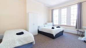 A hotel room with two beds, a wardrobe, a desk, and a window with curtains. - Brookvale Guest House Room 2 (Southampton)