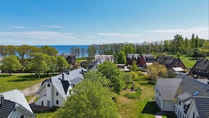 A residential area with houses, green lawns, and a view of the sea. - Beachfront vacation rental with a terrace, access to the pool and sauna - Rex Rugia (Mönchgut OT Lobbe)