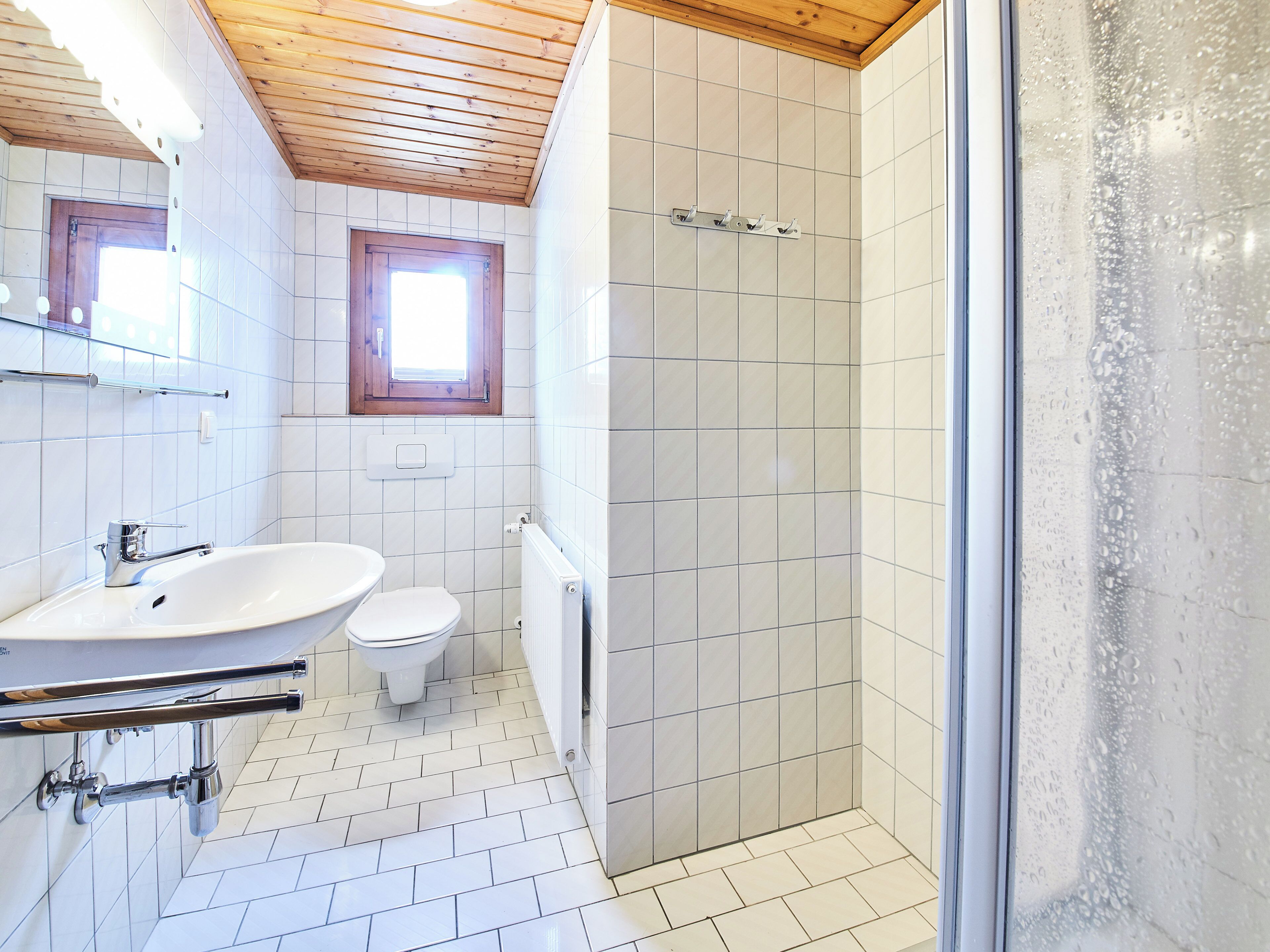 A bathroom with a white sink, toilet, and shower area.