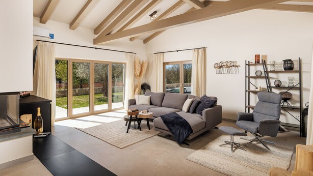A modern living room with a sofa, armchair, and a fireplace.
