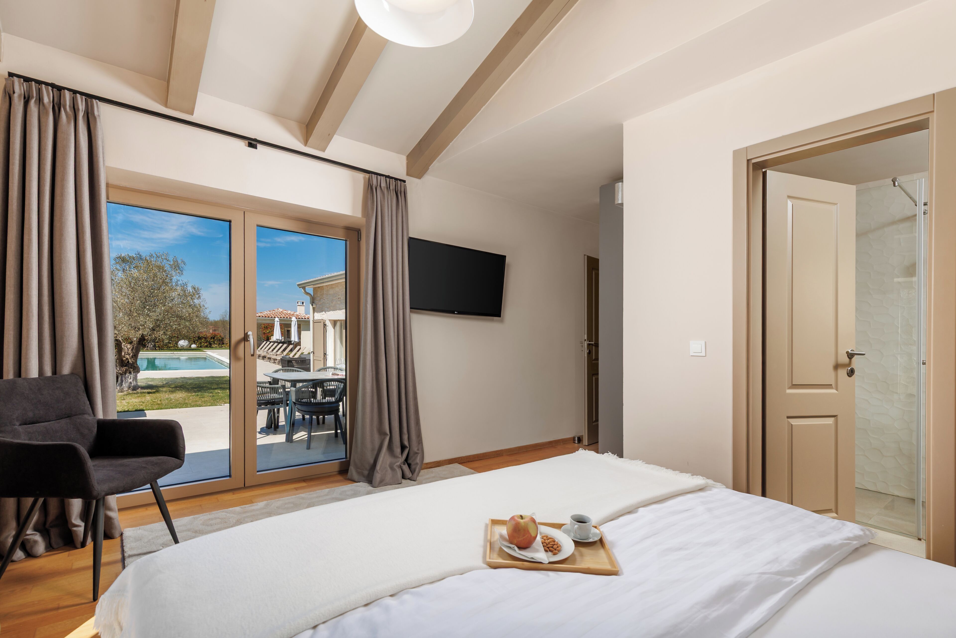Un dormitorio con cama, televisor, puerta corrediza a un patio y ducha.