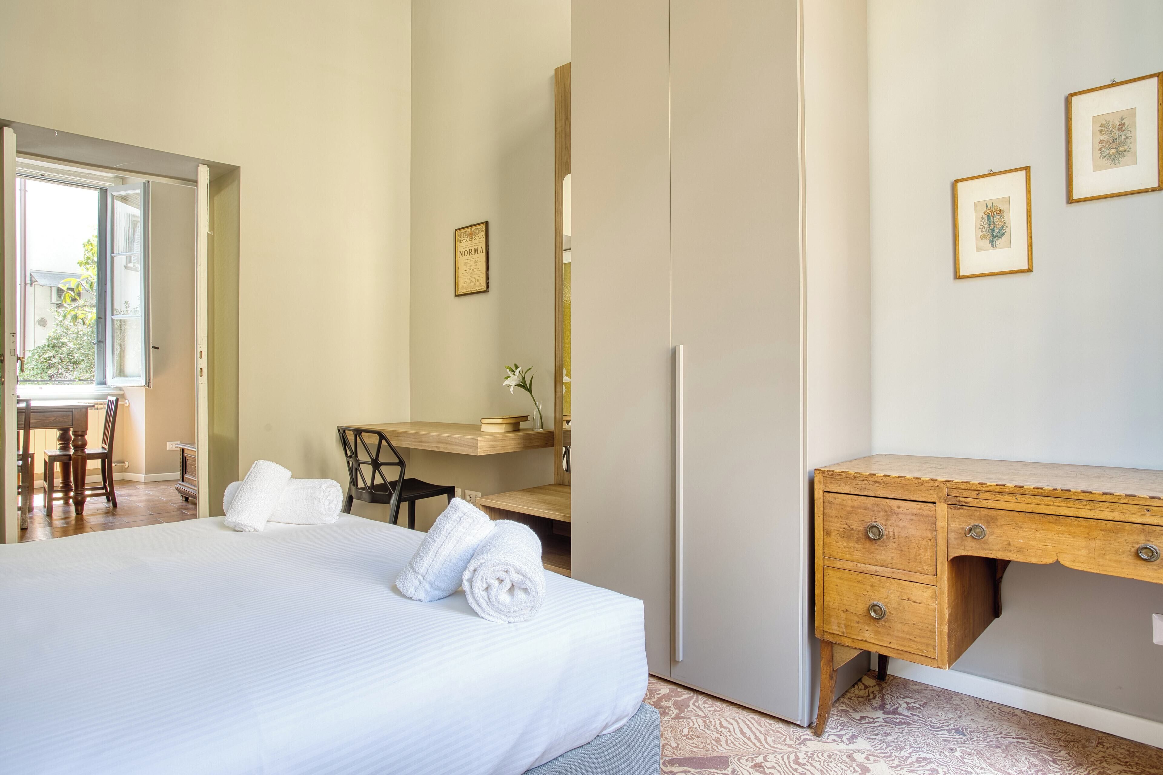 A hotel room with a bed, a desk, and a wardrobe.