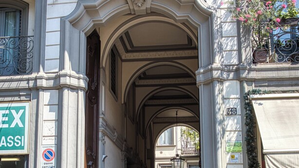 Une entrée architecturale richement décorée, avec une arche centrale, une enseigne indiquant « Affitti » et une porte bien visible.