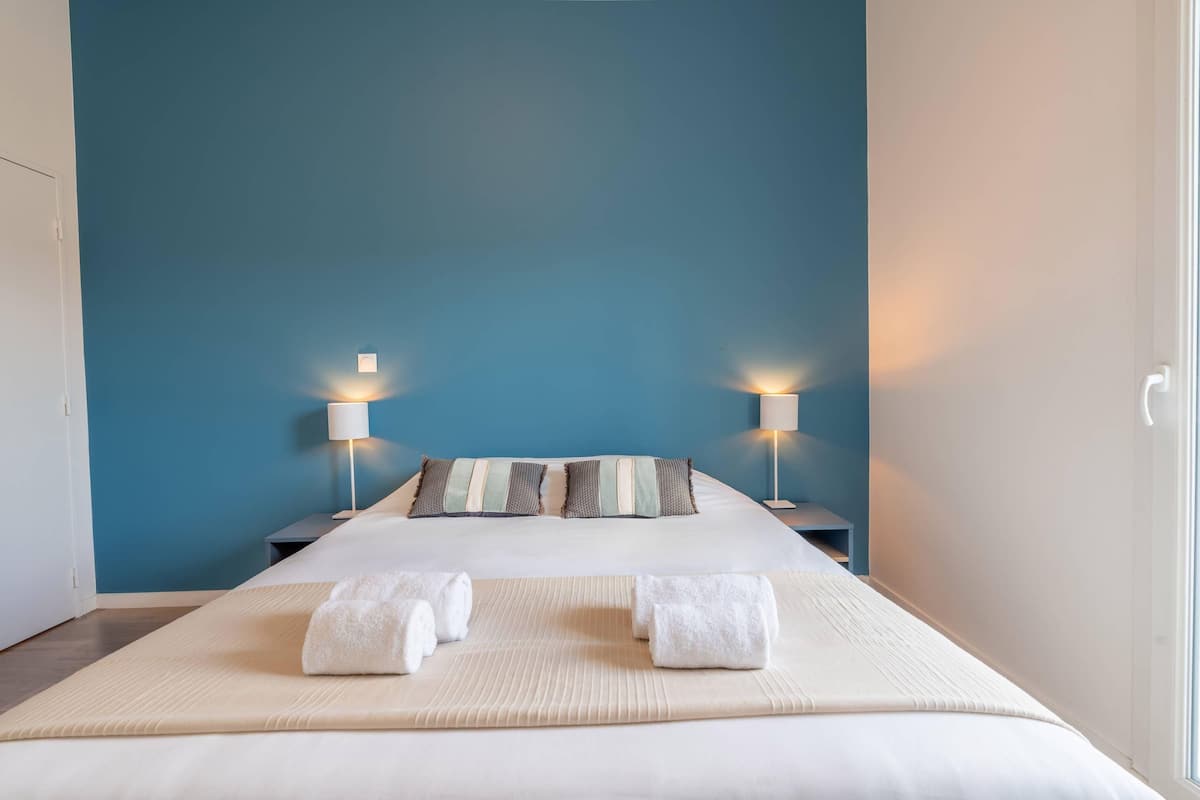 Une chambre d’hôtel avec un grand lit, deux lampes de chevet et une vue sur l’extérieur.