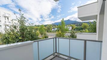 Uma varanda com grade de metal, com vista para uma área residencial com árvores e edifícios.