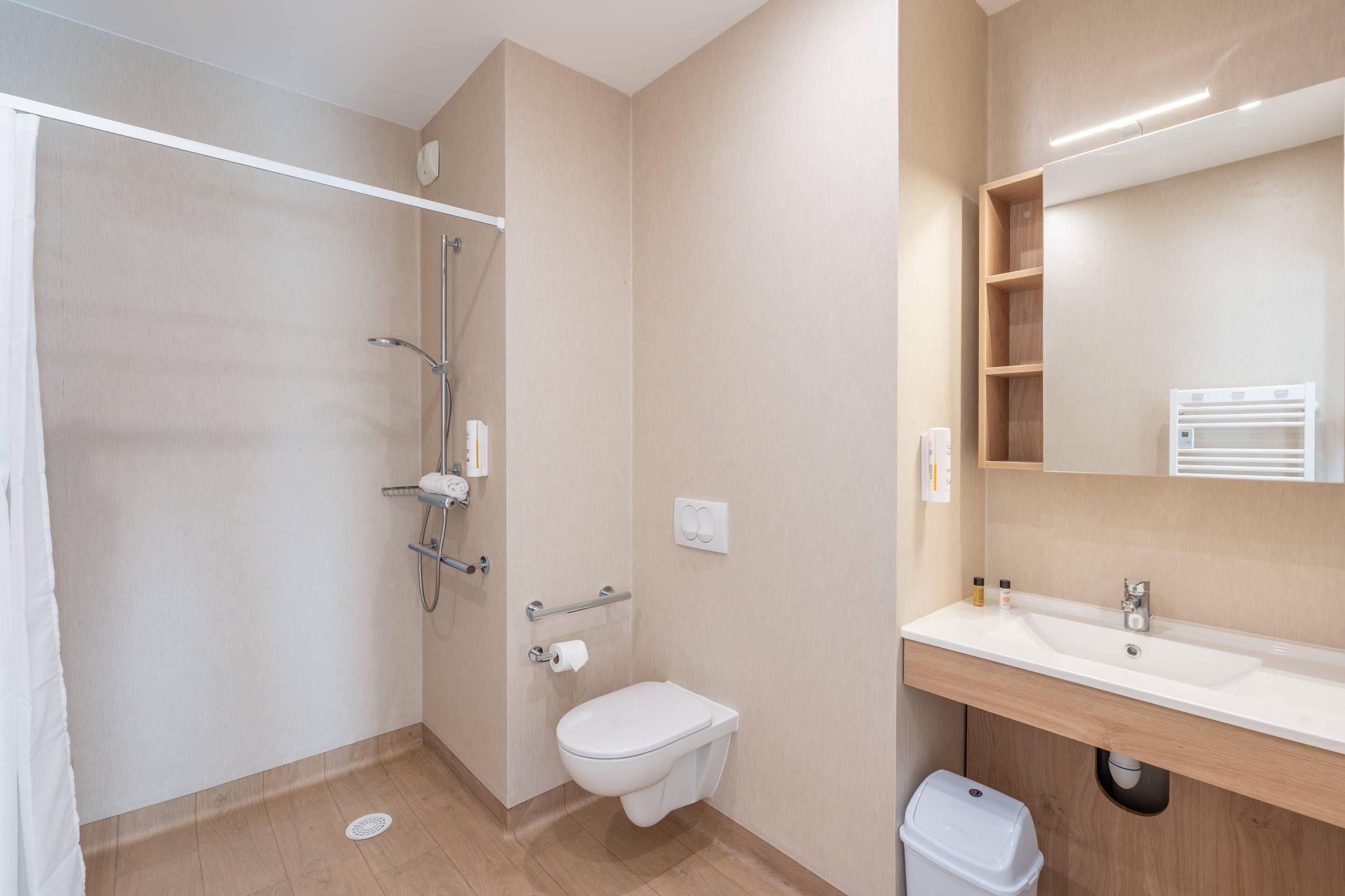 A bathroom with a shower, toilet, sink, and a mirror.