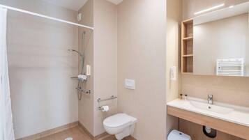 A bathroom with a shower, toilet, sink, and a mirror.