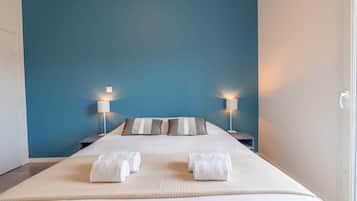 A hotel room with a large bed, two bedside lamps, and a view of the outside.