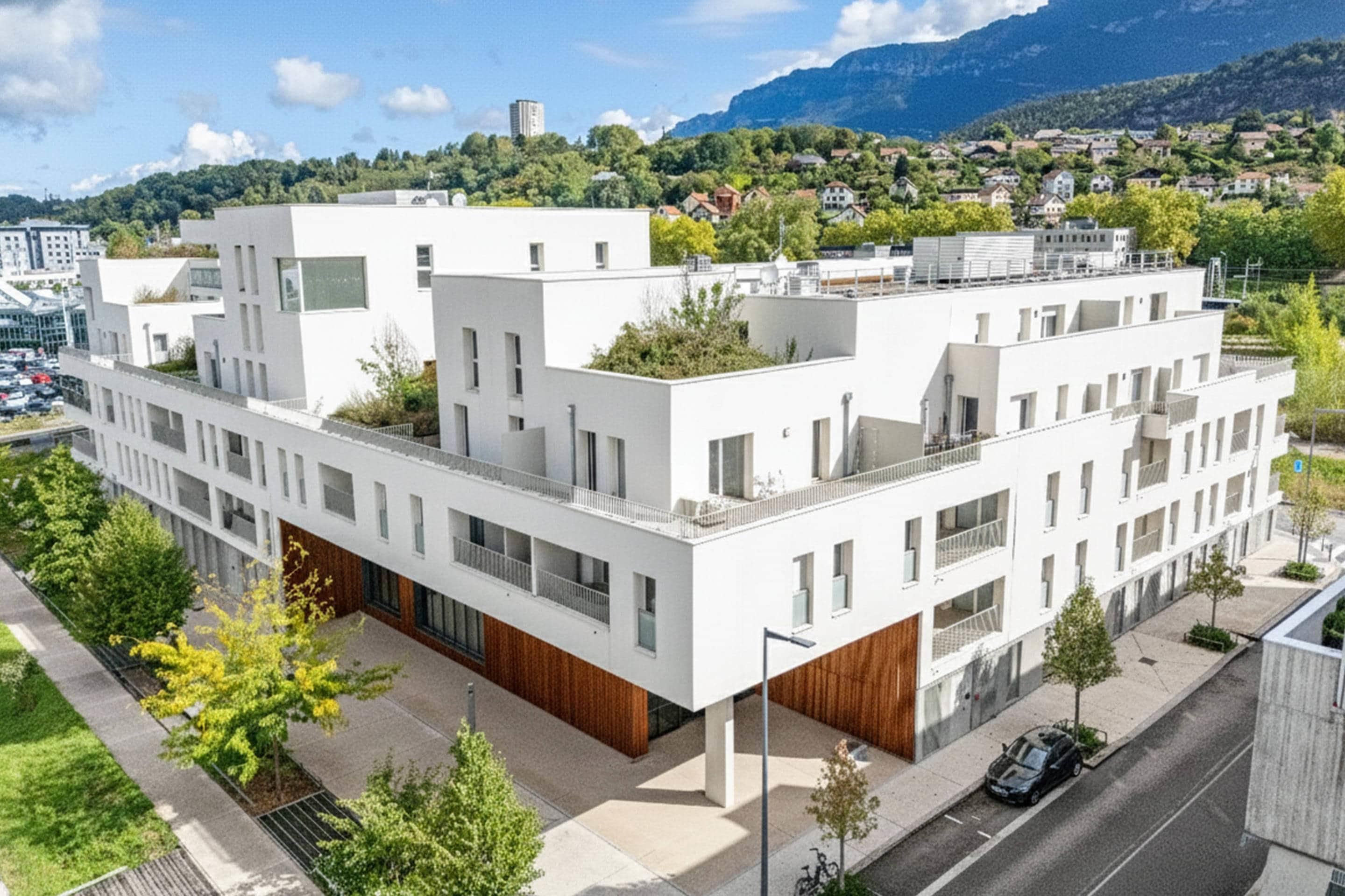 A modern multi-story building with a flat roof, large windows, and a wooden facade.