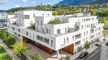 A modern multi-story building with a flat roof, large windows, and a wooden facade.