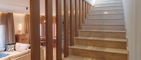 A staircase with wooden handrails and beige steps leading to a second floor.