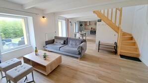 Amplia sala de estar con un sofá gris, una mesa de centro de madera y una escalera.