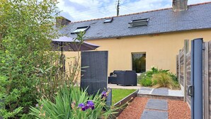 Una casa moderna con jardín, mobiliario de exterior y una pérgola.