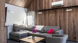A modern living room with a grey sectional sofa, a wooden coffee table, and a red heart-shaped pillow. - Villa in Belgium with Private Terrace (La Roche-en-Ardenne)