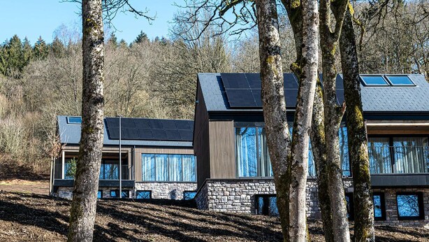 A modern house with solar panels, large windows, and stone walls, surrounded by trees. - Villa in Belgium with Private Terrace (La Roche-en-Ardenne)