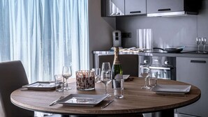 A dining table set with plates, cutlery, glasses, and a bottle of champagne in a modern kitchen with grey cabinets and stainless steel appliances. - Villa in Belgium with Private Terrace (La Roche-en-Ardenne)