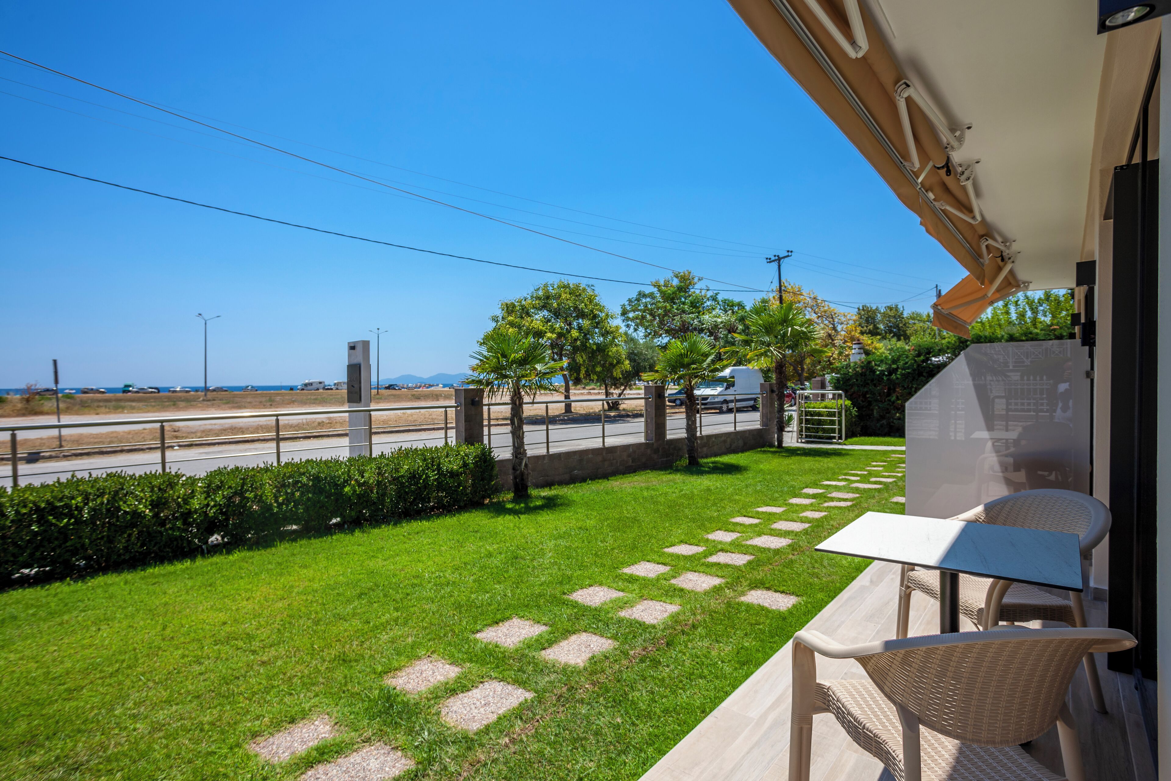 Un balcon donnant sur la rue, un espace verdoyant agrémenté de pas japonais et du mobilier d’extérieur.