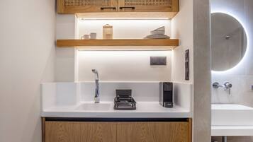 A modern bathroom with a white sink, wooden cabinets, a built-in heater, and a round mirror.