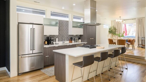 A modern kitchen with a central island, stainless steel appliances, and a dining area with a view.